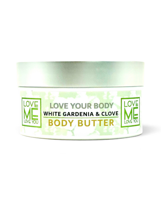 A white jar of Love Me Body Butter with a silver lid, featuring a label that reads 'White Gardenia & Clove Body Butter' in black and green text.