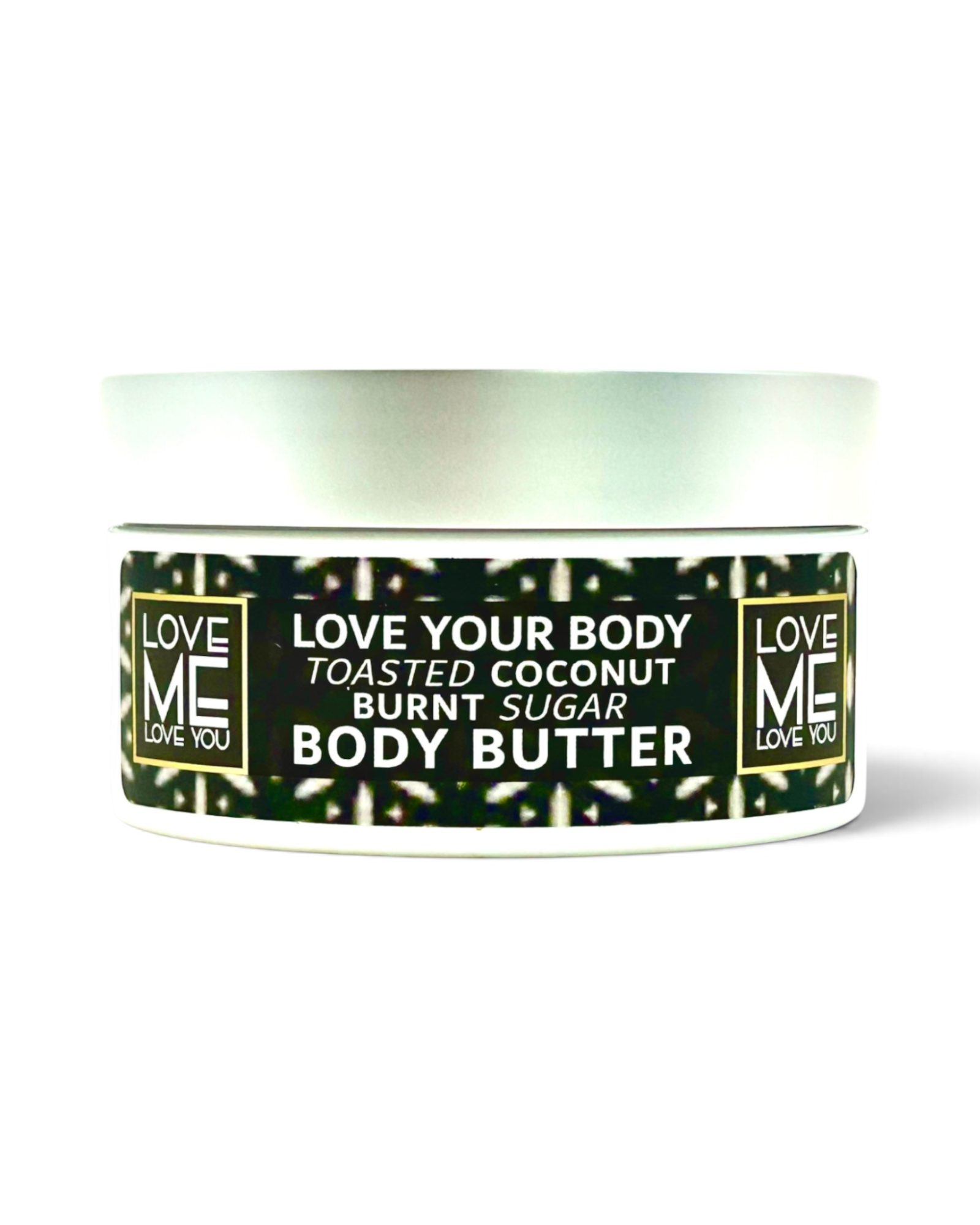 A jar of Love Me Body Butter in the Toasted Coconut Burnt Sugar scent, featuring a white container with a black and green patterned label and a silver lid, set against a plain white background.